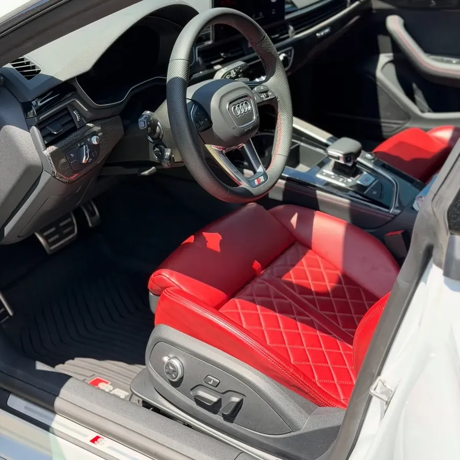 Red leather seats and black floor mats inside a detailed Audi